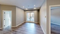 Located at 11235 105 Ave NW in Edmonton, Alberta, this well-appointed 2-bedroom, 2-bathroom unit offers a thoughtfully designed single-floor layout ideal for comfortable everyday living. The open-concept living, dining, and kitchen area forms the heart of the home, characterized by light-toned laminate flooring, neutral grey walls, and recessed lighting that creates a bright and welcoming atmosphere. The kitchen is a standout feature, boasting wood-grain cabinetry, a large island with a white quartz countertop and undermount double sink, a subway tile backsplash, and a full suite of stainless steel appliances including a French door refrigerator, electric range, and built-in microwave. Stylish pendant lighting adds a modern finishing touch above the island. Both bedrooms are well-proportioned with laminate flooring and access to closet storage. The primary bedroom benefits from a sliding glass door with outdoor views. A flexible den provides additional space suited for a home office or study. The two bathrooms are finished in a clean, contemporary style, each featuring a soaker tub and shower combination with chrome fixtures and tile surrounds. Additional conveniences include in-unit laundry and multiple closets for generous storage throughout.