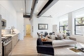 This 640 square foot apartment showcases a thoughtful, modern design that maximizes space efficiency. The single-floor layout comprises four main areas: a bedroom, a living area, a kitchen, and a bathroom. 

The bedroom features a queen-sized bed with a rattan headboard, built-in closet space with sliding doors, and carefully curated artwork adorning the walls. Large windows allow ample natural light, creating a bright and airy atmosphere.

The living area doubles as a home office, with a sleek yellow desk positioned near the window to take advantage of natural light. A comfortable sofa, modern TV stand, and strategically placed plants contribute to a cozy yet functional space.

The kitchen boasts a contemporary design with white upper cabinets and wood-toned lower cabinets. Stainless steel appliances, including a gas range and over-the-range microwave, complement the quartz countertops. A distinctive geometric backsplash adds visual interest.

The bathroom, though compact, is well-appointed with a modern toilet, stylish fixtures, and a clean, minimalist design. Large-format tiles in a neutral tone create a sense of spaciousness.

Throughout the apartment, light wood flooring unifies the space, while white walls provide a neutral backdrop for the carefully selected furniture and decor. The overall design aesthetic is clean, contemporary, and highly functional, making excellent use of the available square footage.