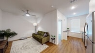 This single-floor residence offers a thoughtfully designed layout that balances comfort and functionality. The living area is bright and welcoming, featuring warm hardwood flooring, white walls, and a ceiling fan that adds both style and practicality. Recessed lighting complements the natural light filtering through the windows, creating an airy and open atmosphere throughout the space.

The kitchen is well-appointed with crisp white cabinetry, dark granite countertops, a classic white subway tile backsplash, and stainless steel appliances including a microwave, electric range, and dishwasher. A deep stainless steel sink with a pull-down faucet serves as a central feature, and under-cabinet lighting enhances both visibility and ambiance. A small breakfast bar area connects the kitchen to the rest of the living space.

The bedroom is a serene retreat, bathed in natural light from a large window fitted with blinds. The room offers a clean, minimalist aesthetic with neutral tones and hardwood flooring that carries throughout the home.

The bathroom is finished with full white subway tile surrounding the soaking tub and shower combination, complemented by brushed nickel fixtures. Built-in shelving provides convenient storage. Together, these spaces form a cohesive, modern residence with clean lines and well-chosen finishes.