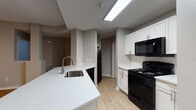 This single-floor residence is designed with a practical, open layout that connects the main living areas seamlessly. The kitchen serves as a central hub, featuring white shaker-style cabinetry, white quartz countertops, and a classic white subway tile backsplash. Black appliances — including a refrigerator, electric range with over-the-range microwave, and dishwasher — provide a clean contrast to the bright cabinetry. A peninsula with an undermount sink adds functional workspace and casual dining potential, opening directly to the living and dining area.

The living room is a comfortable, well-proportioned space anchored by a fireplace with a tile surround and built-in niche above. A ceiling fan, sliding glass door leading to an outdoor area, and access to natural light enhance the room's appeal. Wood-style flooring runs consistently throughout the main living spaces, while a hallway connects to the private areas of the home.

The bedrooms offer natural light through double windows. The bathrooms each include a soaking tub and shower with white square tile surrounds, wood-style flooring, and white vanities. A dedicated laundry room accommodates a full-size washer and dryer, with wire shelving above for additional storage. Neutral gray walls throughout create a cohesive, move-in-ready aesthetic.