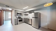 Located at 742 S Westlake Ave in Los Angeles, this modern one-bedroom, one-bathroom unit offers a thoughtfully designed layout across a single floor. The space features a clean, contemporary aesthetic with smooth epoxy-style flooring and neutral grey tones carried consistently throughout.

The kitchen is well-appointed with a full suite of stainless steel appliances, including a gas range, over-the-range microwave, dishwasher, and full-size refrigerator. Sleek grey wood-grain cabinetry, open floating shelves, and a white countertop with an integrated sink complete the functional and modern kitchen design, illuminated by recessed linear lighting.

The bedroom is a comfortable, well-proportioned room featuring a large window that brings in natural light and provides views of the surrounding Los Angeles cityscape. A mirrored sliding closet offers convenient built-in storage. The room connects directly to the hallway, creating an efficient and accessible flow through the unit.

The bathroom is clean and contemporary, featuring a grey wood-grain vanity with a countertop sink, a lighted mirror, and a full bathtub with shower. The entry hallway provides a practical transition into the main living areas. Overall, the unit presents a minimalist, modern design well-suited for urban living in the heart of Los Angeles.