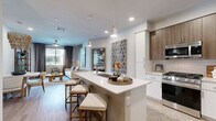 Located at 1820 E Apache Blvd in Tempe, Arizona, this modern three-story townhome offers a well-designed layout across three distinct levels. The entry-level features a private garage with a concrete floor and an adjacent staircase leading to the main living areas above.

The second floor serves as the heart of the home, hosting an open-concept living room, dining area, and kitchen. The kitchen is a standout, featuring stainless steel appliances including a gas range, over-the-range microwave, and French door refrigerator. Cabinetry is a sophisticated two-tone mix of warm wood-grain upper cabinets and crisp white lower cabinets, complemented by a neutral subway tile backsplash and a large center island with a sink. Light wood-style flooring runs throughout this level, and a convenient half bathroom with a pedestal sink and a pantry round out this floor.

The third floor is home to two bedrooms, including the primary suite with balcony access, a ceiling fan, and generous natural light. The second bedroom features plush carpeting and dual windows with outdoor views. Three closets and a dedicated laundry area provide ample storage. The bathrooms are finished in a clean, contemporary style with light-toned flooring and white fixtures. Carpeted staircases with metal railings connect all three levels seamlessly.