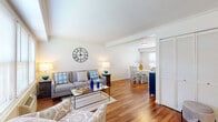 This two-story home is thoughtfully laid out across two equal floors, offering a practical and comfortable living arrangement. The main level opens into a bright living room featuring rich hardwood flooring, neutral white walls, and natural light streaming through multiple windows. The living area flows seamlessly into a dedicated dining space, which benefits from its own window overlooking the outdoors, and connects to the kitchen. The kitchen is well-equipped with warm wood cabinetry, granite countertops, stainless steel appliances including a gas range, dishwasher, and refrigerator, and a back door providing additional access. A staircase with a classic wood banister leads to the upper level, where both bedrooms are located. The spacious primary bedroom features the same warm hardwood flooring and offers ample room for furnishings. The second bedroom is comparably comfortable. The single full bathroom features tile flooring, a granite-topped vanity with dark wood cabinetry, a window for natural light, and a tub-shower combination. Throughout the home, a consistent palette of white walls and hardwood floors creates a cohesive and inviting atmosphere.