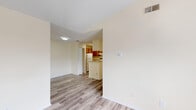 This single-story home offers a well-organized layout across three bedrooms and two bathrooms. The living area serves as the heart of the home, featuring notable vaulted ceilings that lend a sense of openness and volume to the space. A ceiling fan is installed overhead, and a window allows natural light to fill the room. The flooring throughout the main living areas and kitchen consists of durable wood-look laminate planks in a neutral gray-brown tone, providing a cohesive and easy-to-maintain surface.

A central hallway connects the living area to the rest of the home, with the kitchen positioned conveniently nearby. The kitchen is equipped with warm-toned wooden cabinetry, a range, refrigerator, dishwasher, and a sink, all arranged in an efficient layout with a pass-through opening to the adjacent living space.

The three bedrooms are carpeted in a neutral beige tone and each features windows that bring in natural light along with ceiling fans for added comfort. The two bathrooms are identically appointed, each featuring a tub-shower combination with white tile surround, wood-look flooring, and vanity storage. Textured ceilings are present throughout the home, contributing to its consistent aesthetic.