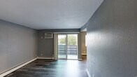 Located at 1944 Kentucky Ave in Cincinnati, Ohio, this single-floor unit presents a cohesive, neutral design palette anchored by wood-style laminate flooring and cool gray walls throughout. The open living area is a standout feature, offering a sliding glass door that leads directly to a private balcony, allowing natural light to fill the space while providing views of surrounding greenery. A wall-mounted air conditioning unit and baseboard heating are present throughout, ensuring year-round comfort.

The living space flows into an adjoining room, visible through an open passage and equipped with a ceiling fan, offering flexible use as a dining area or additional living space. Bedrooms are well-proportioned, each featuring natural light from windows fitted with white blinds, baseboard heating, and wood-style flooring. At least one bedroom includes a sliding-door closet with built-in rod storage.

The kitchen is outfitted with dark wood cabinetry, granite-style countertops, and a stainless steel sink, offering a practical and clean workspace. The bathroom complements the overall design with a granite-topped vanity, dark wood cabinetry, a full tub-shower combination, and light wood-style flooring. The textured ceilings and clean white trim throughout tie the unit together with a consistent, updated aesthetic.