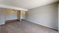 This single-floor unit in Council Bluffs, Iowa offers a practical and comfortable layout across several well-defined living spaces. The main living area is spacious and bright, featuring plush wall-to-wall carpeting, neutral gray walls, and a textured ceiling. A sliding glass door with vertical blinds invites natural light and provides access to an outdoor space, enhancing the open feel of the room. Entry hooks on the wall near the door add a convenient organizational touch.

The kitchen is efficiently designed and equipped with black appliances, including a coil-burner electric range with ventilation hood and a refrigerator. Light gray countertops and white cabinetry provide a clean, functional workspace, while wood-tone flooring grounds the area.

The bedroom is generously proportioned, featuring soft carpeting, a natural light window, and two side-by-side closets with sliding doors and built-in hanging rods — offering ample storage. An additional carpeted room provides flexible space suitable for a second bedroom or office.

The bathroom includes a full tub-shower combination with tiled surround, chrome fixtures, and wood flooring. Throughout the unit, consistent gray tones, white trim, and textured ceilings create a cohesive, understated aesthetic. A ceiling fan is also present, adding comfort to the interior environment.