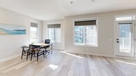 Located in the Sage Meadows community of Calgary, this two-storey home offers four bedrooms, three bathrooms, and a well-designed layout spread across two floors. The main floor is generously sized, housing the primary living areas, while the upper floor provides additional space for bedrooms or flexible use.

The modern kitchen is a standout feature, showcasing crisp white cabinetry, a dark tile backsplash, stainless steel appliances, and a large peninsula with a quartz-style countertop and double undermount sink. Stylish pendant lights hang above the peninsula, adding a contemporary touch. Light wood-look flooring runs throughout the main living areas, enhancing the bright, clean aesthetic.

The living and dining areas connect seamlessly to a private balcony through a sliding glass door, bringing in natural light and outdoor views of the surrounding neighbourhood. The bedrooms are well-proportioned, each featuring closets with sliding doors and roller blinds on the windows. One bedroom benefits from multiple windows with views of the community.

The bathrooms include a clean powder room with a pedestal sink, and a full bath with a soaker tub and shower combination fitted with modern brushed nickel fixtures. Neutral tones and tile flooring carry through each bathroom. Overall, the home presents a fresh, contemporary design with a cohesive palette of whites, greys, and natural wood tones.