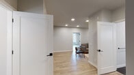 This thoughtfully designed single-floor space delivers a clean, contemporary aesthetic through a cohesive neutral color palette, light hardwood flooring, and recessed lighting throughout. The open layout connects multiple functional areas with ease, beginning with a corridor entry flanked by crisp white panel doors with matte black hardware.

The kitchen is well-appointed with stainless steel appliances, including a full-size refrigerator, stove, and microwave, complemented by sleek grey and white cabinetry and a subway tile backsplash. A solid walnut dining table with modern chairs sits adjacent, creating a practical kitchen-dining area.

The living area offers a comfortable, intimate setting with light hardwood floors, recessed lighting, and wall art, providing a welcoming atmosphere for relaxing or entertaining. Multiple additional rooms feature generous natural light from large windows dressed with neutral linen drapes, offering views of the surrounding neighborhood.

The bathroom is finished to a high standard, showcasing large-format dark floor tiles, a frameless glass sliding shower enclosure with matte black hardware, and a floating wood-toned vanity with an undermount sink. HVAC vents are integrated discreetly throughout, ensuring year-round comfort. The overall ambiance is bright, clean, and move-in ready.