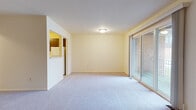 This single-floor, 2-bedroom, 2-bathroom residence offers a functional and comfortable layout across a generously sized floor plan. The living area features wall-to-wall carpeting and is bathed in natural light through large sliding glass doors that open to an outdoor space, providing pleasant exterior views. A pass-through opening connects the living area to the kitchen, creating an open feel between the two spaces.

The kitchen is outfitted with rich, dark wood cabinetry, light countertops, and tile flooring. It includes a full suite of white appliances — a gas range with overhead ventilation, a dishwasher, and a refrigerator — along with a stainless steel sink lining the countertop wall.

Both bedrooms are carpeted and feature windows that bring in natural light and outdoor views. One bedroom includes a spacious walk-in closet with built-in shelving and hanging rods, providing ample storage.

The two bathrooms are finished in clean, white tile. The primary bathroom features a standalone walk-in shower with a framed glass door and grab bar, while the second bathroom offers a shower-tub combination with a sliding glass enclosure and a vanity with a granite-style countertop. Both bathrooms maintain a bright, functional aesthetic throughout.
