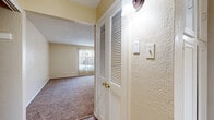 This single-floor residence offers a well-organized layout that balances comfort and functionality throughout its thoughtfully designed spaces. The open living area serves as the heart of the home, featuring warm, neutral-toned carpet, a textured ceiling, and a ceiling fan with light fixture. A large window dressed with vertical blinds floods the room with natural light and offers an outward view, creating an inviting and airy atmosphere. Adjacent to the living area, a pass-through opening connects seamlessly to the kitchen, which showcases granite countertops, crisp white cabinetry, wood-look flooring, and a full-size refrigerator — a clean and practical space for everyday use.

The bedrooms continue the warm, carpeted aesthetic and each feature built-in closet space. One bedroom includes a generously sized walk-in closet with dual shelving and hanging rods on both sides, providing ample storage. Each bedroom benefits from ceiling fans and natural light from windows with blinds. The bathroom is equipped with a full-size soaking tub and shower combination, finished in clean white with chrome fixtures.

Throughout the unit, textured walls, consistent warm beige tones, and wood-look flooring in key areas lend a cohesive and comfortable character to the overall space.