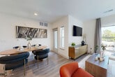 Located at 100 Eisenhower Parkway in Livingston, NJ, this thoughtfully designed one-bedroom, one-bathroom residence offers a seamless blend of modern style and functional living. The open-concept layout connects the kitchen, dining, and living areas into a bright, cohesive space bathed in natural light from large windows that overlook the surrounding community.

The kitchen is a standout feature, equipped with white shaker cabinetry, quartz countertops, a subway tile backsplash, stainless steel appliances, and pendant lighting over the peninsula — which also doubles as a breakfast bar with seating. The living and dining area flows effortlessly from the kitchen, with wood-style flooring and access to a private balcony.

The bedroom is a comfortable retreat, featuring a ceiling fan, large windows with outdoor views, and ample natural light. The well-appointed bathroom includes a dual-sink vanity with white cabinetry and a gray countertop, marble-style tile flooring, and a full tub-shower combination with floor-to-ceiling dark tile surround. A dedicated closet provides practical storage. Clean lines, neutral tones, and contemporary finishes throughout give this residence a polished, modern ambiance.
