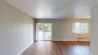 Located at 1800 Stokes St in San Jose, California, this one-bedroom, one-bathroom unit offers a well-designed single-floor layout that makes efficient use of its space. Warm hardwood-style flooring flows consistently throughout, complementing the neutral gray and beige wall tones that create a clean, cohesive aesthetic.

The combined kitchen and living room area forms the heart of the unit. The kitchen is appointed with rich dark espresso cabinetry extending floor to ceiling, white quartz countertops, a subway tile backsplash, stainless steel appliances, and recessed lighting. The adjacent living area is bright and open, featuring a sliding glass door that leads to an outdoor area and an additional window that fills the room with natural light.

The bedroom is a comfortable, well-proportioned retreat featuring a large mirrored sliding closet, a baseboard heater, and a window overlooking lush greenery and flowering trees. The bathroom is finished with a dark wood vanity matching the kitchen cabinetry, a white quartz countertop, a large mirror, and a full shower-tub combination with tiled surround.

A hallway connects the rooms and includes built-in open shelving, adding practical storage. A ceiling fan is present in the dining area near the kitchen, and the unit benefits from greenery views throughout, contributing to a bright and pleasant living environment.