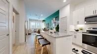 This thoughtfully designed 1-bedroom, 1-bathroom residence offers a seamless open-concept layout that connects the kitchen, dining, and living areas into one cohesive, light-filled space. Light wood-style flooring flows throughout the main living areas, complemented by recessed lighting and a neutral white palette accented by bold teal feature walls that add a vibrant, contemporary character.

The kitchen is outfitted with crisp white shaker cabinetry, granite countertops, a subway tile backsplash, and stainless steel appliances including a refrigerator, range, and over-the-range microwave. A peninsula with seating provides a natural transition into the dining area, which benefits from proximity to the living room and its large windows that invite generous natural light.

The living room is a welcoming retreat, with oversized windows offering outdoor views and a ceiling fan adding comfort. The bedroom features plush carpeting, a softly painted ceiling, and direct access to both the bathroom and a generously sized walk-in closet with wrap-around hanging rods and shelving.

The bathroom is clean and modern, showcasing a granite-topped white vanity, a large mirror, and light wood-style flooring that ties the space together. Every room reflects a practical yet stylish design sensibility throughout.