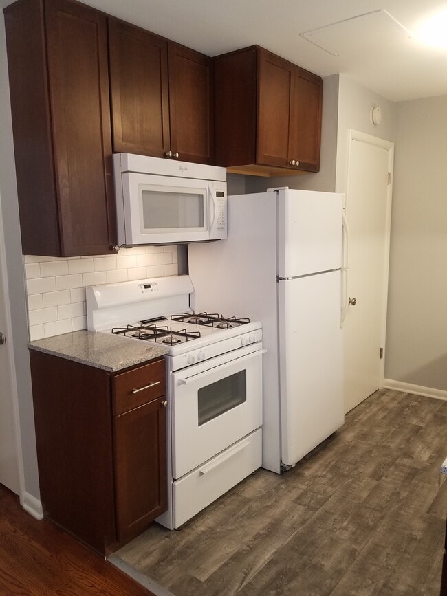 Newer kitchen with granite counters, electric stove, microwave, dishwasher, and cabinets to ceiling - 6644 Walrond Ave