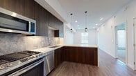 Located at 6606 Variel Ave in the Canoga Park neighborhood of Los Angeles, this modern single-floor residence showcases a thoughtfully designed open layout with contemporary finishes throughout. The kitchen is a standout feature, boasting rich dark wood cabinetry extending to the ceiling, a marble-style tile backsplash, crisp white quartz countertops, and a full suite of stainless steel appliances including a gas range, dishwasher, built-in microwave, and a side-by-side refrigerator. A peninsula with pendant lighting bridges the kitchen to the open living area, creating an inviting, cohesive space ideal for both cooking and entertaining. Wide-plank wood-style flooring runs through the main living areas, adding warmth to the clean, white-walled interiors. Recessed lighting and large windows allow natural light to fill the space. The bedroom features plush carpeting and a glazed door that brings in additional light. The bathroom is finished in a bright, neutral palette with marble-look tile flooring, a tiled shower-tub combination, built-in shelving, and a wood-accented vanity. A stacked in-unit washer and dryer adds practical convenience to this well-appointed home.