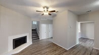 Located at 4447 Rainier St in Irving, TX, this two-story home offers a well-organized layout spread across two floors. The exterior features classic brick construction with a bold red front door, framed by mature trees and a fenced front area. Inside, the main floor opens into a bright living room with wood-look flooring, a ceiling fan, a textured ceiling, and a white corner fireplace that serves as a focal point. Natural light filters through windows, creating a welcoming atmosphere. The adjoining dining area connects seamlessly to the kitchen, which is equipped with white cabinetry, light quartz-style countertops, and black appliances including a range and over-the-range microwave. A convenient half or full bathroom and a laundry area round out the main level, along with access to one of two patios. A staircase leads to the upper floor, where two bedrooms are situated. The spacious primary bedroom features high ceilings with shiplap detailing, dual closets, and an en-suite bathroom. The second bedroom benefits from natural light through a large window. The upper level also includes additional bathrooms featuring wood-look flooring, wide vanities with light countertops, and clean, neutral finishes. Four closets throughout the home provide generous storage.