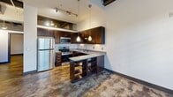 This contemporary 830 sq ft apartment in Winston-Salem, NC, seamlessly blends industrial and modern design elements. The space boasts two bedrooms, including a 140 sq ft primary bedroom, and two full bathrooms. Upon entry, one is greeted by striking high ceilings with exposed ductwork, creating an open and airy atmosphere.

The apartment features polished concrete floors throughout, adding to its industrial charm while providing durability and easy maintenance. Large windows flood the living areas with natural light, enhancing the sense of spaciousness. The kitchen is a highlight, showcasing dark wood cabinetry, stainless steel appliances, and granite countertops. A central island with open shelving serves as both a functional workspace and a stylish focal point.

Both bathrooms are designed with modern fixtures, including sleek tub-shower combinations and ample storage. The bedrooms offer generous space and closet areas. Throughout the apartment, the contrast between light walls and dark trim accentuates the architectural details.

The open floor plan allows for versatile living arrangements, making it ideal for both relaxation and entertaining. With its blend of industrial elements and contemporary finishes, this apartment offers a unique living experience in the heart of Winston-Salem.