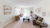 This single-floor residence is thoughtfully laid out with a neutral color palette, soft carpet throughout the main living areas, and light-toned walls that create a cohesive, airy atmosphere. The living room is generously proportioned, featuring multiple windows and a sliding glass door that opens to a balcony, filling the space with natural light and providing outdoor views. Adjacent to the living room, the dining area accommodates a round table for four and includes a ceiling fan fixture overhead, with an open sightline into the primary bedroom corridor.

The kitchen is well-appointed with white cabinetry, granite-style countertops, light tile flooring, and a full suite of stainless steel appliances including a refrigerator, range, and over-the-range microwave. A window above the sink adds natural light to the workspace.

The primary bedroom is spacious with plush carpeting, a dedicated walk-in closet, and a neutral tone that lends a calm, restful quality. Two additional bedrooms offer comfortable proportions, each with carpeted floors and windows admitting natural light. The bathroom features tile flooring, a shower/tub combination, and a granite-topped vanity, maintaining the clean, consistent aesthetic found throughout the residence.