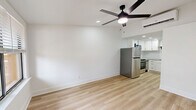 Located at 2875 Palumbo Dr in Lexington, KY, this efficiently laid-out studio offers a clean, modern aesthetic across a single floor. The combined kitchen and living area is anchored by light-toned hardwood flooring that runs throughout, creating a bright and cohesive feel. Crisp white walls and recessed lighting keep the space feeling open and airy, while a ceiling fan with a sleek black finish adds both function and style to the living area. A window with horizontal blinds allows natural light to filter in, offering a view of the surrounding greenery outside.

The kitchen is well-appointed with white shaker-style cabinetry accented by matte black hardware, a classic white subway tile backsplash, and stone-look countertops. Stainless steel appliances, including a full-size LG refrigerator and a range, provide modern functionality. A black utility sink faucet completes the kitchen's contemporary design. The kitchen flows naturally into the living space, making the layout practical for everyday use.

The bathroom features a clean, minimalist design with a shower/tub combination and a matte black towel bar accent, maintaining the consistent modern style found throughout the rest of the space. Overall, this studio presents a thoughtfully updated interior with a neutral palette ideal for comfortable, efficient living.
