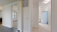 This single-floor, one-bedroom, one-bathroom residence offers a thoughtfully arranged layout that maximizes functionality and comfort. The living room is bright and inviting, featuring rich dark hardwood-style flooring, a ceiling fan with integrated lighting, and large windows fitted with blinds that allow for ample natural light and outdoor views. A glass-paneled door provides additional light and exterior access directly from the living area.

The kitchen is equipped with striking granite countertops, dark cabinetry, and a built-in counter-height workspace — an ideal setup for both cooking and casual use. Hardwood-style flooring continues throughout this area, complementing the clean, neutral color palette carried across the entire space.

The hallway serves as a central connector, finished with light tile flooring and featuring a wall-mounted thermostat and overhead HVAC vent, reflecting practical design throughout. The spacious bedroom is carpeted for comfort and includes a ceiling fan, a generous window with natural views, and direct access to both the bathroom and a large walk-in closet. The walk-in closet is outfitted with multi-level wire shelving on all walls, offering extensive storage capacity. A second closet provides additional storage convenience. The bathroom is clean and functional, accessible from both the hallway and the bedroom.