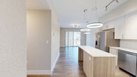 Located at 200 Daytona Blvd in Daytona Beach, FL, this thoughtfully designed two-bedroom, one-bathroom residence offers a clean, contemporary aesthetic throughout its efficiently utilized single-floor layout. Wood-look flooring flows seamlessly through the main living areas, complementing the neutral, warm-toned walls that create a bright and welcoming atmosphere.

The open-concept kitchen is a standout feature, equipped with stainless steel appliances including a French door refrigerator, range, microwave, and dishwasher. Flat-front cabinetry in white and light wood tones pairs with crisp white quartz countertops and a central island, illuminated by striking circular pendant lights that add a modern touch.

The living area extends toward a balcony through full-length vertical blinds, allowing natural light to filter into the space and offering outdoor access. Both bedrooms feature the same wood-look flooring and bright windows with exterior views. The spacious primary bedroom includes a dedicated walk-in closet with wire shelving.

The bathroom is finished with large-format tile flooring, a tub-shower combo with marble-style tile surround, and a white vanity with brushed nickel hardware. Additional conveniences include a dedicated laundry area and utility room, rounding out this well-appointed Daytona Beach residence.
