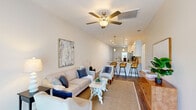 Located at 3905 Bahama Dr in Wildwood, Florida, this well-appointed single-story home offers three bedrooms, two bathrooms, and a thoughtfully designed open-concept floor plan. The bright living room features light wood-style flooring, a ceiling fan, and sliding glass doors that invite natural light and outdoor views. Adjacent to the living area, the dining space benefits from large windows and a clean, airy aesthetic with vaulted ceiling accents. The kitchen is outfitted with crisp white shaker cabinetry, granite-style countertops, a subway tile backsplash, and stainless steel appliances, offering both style and functionality. The primary bedroom is a comfortable retreat with its own walk-in closet equipped with wire shelving for ample storage. Additional bedrooms feature windows with natural light and ceiling fans. The bathrooms are finished with granite vanity tops, white cabinetry, wood-look flooring, and a glass-enclosed walk-in shower. A dedicated laundry room houses a full-size washer and dryer. The home sits within a community that includes a pool area and landscaped common grounds, visible from the exterior. Light neutral tones and consistent wood-look flooring throughout give the home a cohesive, modern feel.