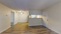 Located at 2930 Linden Ln in Carmichael, CA, this one-bedroom, one-bathroom residence offers a well-designed single-floor layout with light-toned laminate wood flooring throughout. The open-concept living, dining, and kitchen area forms the heart of the home, anchored by a classic fireplace with a tiled hearth and sliding glass doors leading to a private balcony with views of mature surrounding trees. Ceiling fans provide additional comfort in the main living area. The kitchen features a peninsula counter with upper and lower white cabinetry, stainless steel refrigerator, electric range, dishwasher, and a window above the sink that brings in natural light. The spacious bedroom offers ample room for furnishings, a mirrored sliding-door closet, and a large window with pleasant green views. The bathroom includes a full-size soaking tub and shower combo with a grab bar and clean white tile surround. Additional spaces include a utility room, hallway, and dedicated closet storage. Textured ceilings are present throughout, and the neutral color palette gives the space a bright, clean, and move-in ready feel.