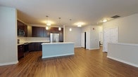 Located at 8370 S Orchard Way in Oak Creek, Wisconsin, this single-floor unit offers a well-designed, open-concept layout with thoughtful finishes throughout. The kitchen serves as a central highlight, featuring rich dark cabinetry, light countertops, and a suite of stainless steel appliances including a refrigerator, range, microwave, and dishwasher. A generously sized center island with an undermount sink and pendant lighting overhead adds both functionality and visual appeal, seamlessly connecting the kitchen to the open living area. Wood-look plank flooring runs throughout the main living spaces, providing a warm and cohesive aesthetic.

The living area benefits from natural light through large windows dressed with blinds, creating a bright and welcoming atmosphere. The bedroom is carpeted for added comfort and also features a window that brings in natural light. The bathroom is finished with dark cabinetry, a white countertop vanity, wood-look flooring, and a walk-in glass-enclosed shower. A stacked washer and dryer unit is also present within the unit, offering added convenience. Overall, the space presents a clean, modern aesthetic with consistent, quality finishes throughout.
