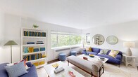 Located at 1717 SW Park Ave. in Portland, Oregon, this 2-bedroom, 1-bathroom unit offers a thoughtfully designed single-floor layout. The entrance leads into a clean, white-walled corridor that opens to a generous living room filled with natural light from a wide, panoramic window framing verdant tree canopy views. The living area features hardwood flooring, ample space for seating arrangements, and a built-in bookshelf, creating a comfortable and functional gathering space. The galley-style kitchen is outfitted with dark espresso cabinetry, light quartz countertops, a tile backsplash, stainless steel appliances including a refrigerator, range, microwave, and dishwasher, and a deep double sink. The primary bedroom is a serene retreat with herringbone-patterned accent wallpaper, hardwood floors, a large pendant light fixture, a closet, and a window overlooking greenery. The second bedroom offers a creative atmosphere with a bold geometric accent wall, ceiling fan, carpeting, and a window with natural light. The full bathroom includes a pedestal sink, mirrored medicine cabinet, and a tub-shower combination. Three closets throughout the unit provide ample storage.