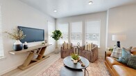 This two-story home is designed with a clean, contemporary aesthetic carried consistently throughout. Light-toned luxury vinyl plank flooring runs across the main level, complementing the neutral white walls and recessed lighting that give each room a bright, airy feel.

The kitchen is outfitted with flat-front wood-toned cabinetry, white quartz countertops, a subway tile backsplash, and a full suite of stainless steel appliances including a range, microwave, dishwasher, and French door refrigerator. A pantry provides additional storage. The adjacent dining area features wainscoting-style detailing and is illuminated by recessed lighting, creating a welcoming space for meals.

The living area offers multiple windows dressed with white horizontal blinds, allowing generous natural light while maintaining privacy. A second living or sitting area shares the same warm, neutral palette.

The primary bedroom is carpeted for comfort and features large windows, soft recessed lighting, and direct access to an en-suite bathroom. The en-suite includes a wide wood-toned vanity, white quartz countertop, an oversized mirror, and a shower-tub combination. A secondary bathroom mirrors this refined style with similar finishes and a tub-shower combo. The overall ambiance is calm, cohesive, and move-in ready.