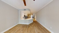 This well-appointed two-floor residence offers a thoughtfully designed layout with a seamless blend of comfort and modern finishes. The main level showcases an open-concept living and kitchen area with warm wood-look flooring, neutral walls, and a ceiling fan overhead. The kitchen is outfitted with white shaker-style cabinetry, a classic subway tile backsplash, white quartz countertops, stainless steel appliances including a range, over-the-range microwave, and refrigerator, and a peninsula with an integrated sink — ideal for casual dining and entertaining. A staircase with a sleek black metal railing connects the two floors, drawing natural light down from above. The upper level features generously sized bedrooms with plush carpeting, vaulted ceilings, and ceiling fans. Each bedroom benefits from access to well-finished bathrooms, one of which includes a glass-enclosed walk-in shower with white subway tile, a mosaic tile floor, and a floating vanity with brushed nickel fixtures. Additional rooms on the main level feature wood-look tile flooring and large windows that invite natural light. Throughout the home, a neutral color palette, clean white trim, and consistent finishes create a cohesive, move-in-ready atmosphere.