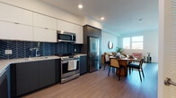 Located at 3975 Wilshire Boulevard in Los Angeles, this one-bedroom, one-bathroom unit offers a well-designed, contemporary living environment with thoughtful finishes throughout. The open-concept layout connects the kitchen, dining, and living areas seamlessly, creating a cohesive and functional flow across the single floor.

The kitchen is a standout feature, showcasing dark lower cabinetry paired with crisp white upper cabinets, a bold navy herringbone-patterned tile backsplash, light granite countertops, and a full suite of stainless steel appliances including a gas range, built-in microwave, refrigerator, and dishwasher. Wood-look flooring runs throughout the main living areas, adding warmth to the modern aesthetic.

The living area benefits from abundant natural light through large windows that frame views of the surrounding Los Angeles cityscape, including distant hills and palm trees. The bedroom features a built-in closet with organizational shelving, balcony access, and ample natural light. The bathroom is finished with large-format tile flooring, a dark wood vanity with marble-style countertop, and an illuminated frameless mirror. A stacked in-unit laundry closet adds everyday convenience.