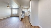 This efficiently designed 1-bedroom, 1-bathroom single-floor residence offers a thoughtful layout that maximizes every square foot. The combined kitchen and living area forms the heart of the unit, where rich wood-look vinyl flooring runs throughout, complemented by neutral-toned walls and a ceiling fan with light fixture. A corner fireplace unit adds a distinctive focal point to the living space, which receives natural light through a large front-facing window.

The galley-style kitchen is well-equipped with crisp white cabinetry, stone-look quartz countertops, a stainless steel double-basin sink, and stainless steel appliances. A window above the counter brings in additional natural light, enhancing the bright and clean aesthetic. Ample upper and lower cabinet storage makes the kitchen highly functional.

The bedroom offers comfortable proportions with plush wall-to-wall carpeting, a large window with blinds, and an impressive dual sliding-door closet configuration that provides generous storage capacity. The full bathroom is finished in a clean, neutral palette featuring a white vanity, a tub/shower combination with tiled surround, and wood-look flooring. A frosted window provides privacy while allowing natural light. A hallway connects all areas of the unit, creating a smooth and logical flow throughout the home.