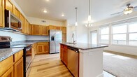 This single-floor residence offers a thoughtfully designed open-concept layout that seamlessly connects the kitchen, dining, and living areas. The kitchen is a standout feature, showcasing warm honey-toned wood cabinetry, granite countertops, and a full suite of stainless steel appliances including a side-by-side refrigerator with ice maker, electric range, microwave, and dishwasher. A large center island with an integrated sink provides additional workspace and casual seating, while pendant lighting and a chandelier add an elegant touch to the space. Light hardwood flooring runs throughout the main living and kitchen areas, lending warmth and continuity.

The bedrooms are carpeted for comfort and receive generous natural light through large windows that frame sweeping views of open fields and distant mountains. Each bedroom benefits from ceiling fans and easy access to well-appointed bathrooms featuring wood cabinetry, granite countertops, and a tub-shower combination. The living area is bright and open, with large windows and a sliding door that flood the space with natural light. Throughout the residence, neutral wall tones, clean white trim, and recessed lighting create a clean, modern aesthetic suited to a variety of interior styles.