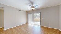 This single-floor residence offers a clean, modern aesthetic highlighted by warm light wood flooring that flows consistently throughout every room. The open living area is bright and welcoming, featuring crown molding, a ceiling fan with light fixture, and a full-width sliding glass door dressed with vertical blinds that opens to an outdoor area, filling the space with natural light and providing a seamless indoor-outdoor connection.

The kitchen is thoughtfully designed with crisp white shaker cabinetry, granite-look countertops, a tile backsplash, and a full suite of stainless steel appliances including a range, over-the-range microwave, and refrigerator. A peninsula with pendant lighting connects the kitchen to the living area, while a dedicated laundry closet with washer and dryer hookups is conveniently accessible nearby.

The bedrooms are generously proportioned, each featuring ceiling fans, large windows with outdoor views, and ample natural light. At least one bedroom includes a walk-in closet, offering notable storage capacity. The bathrooms are finished with granite-topped white vanities, large mirrors, and tub-shower combinations with clean white tile surrounds, maintaining the home's cohesive, contemporary style throughout.