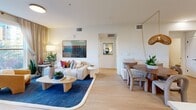 Located at 777 W Middlefield Road in Mountain View, CA, this thoughtfully designed single-floor residence offers 1 bedroom, 2 bathrooms, a den, and an array of well-appointed spaces. The open-concept layout seamlessly connects the kitchen, dining area, and living room, creating a bright and airy main living space bathed in natural light from large windows and a sliding glass door leading to a private patio with outdoor views. The kitchen is outfitted with sleek gray cabinetry, stainless steel appliances, a geometric tile backsplash, and white countertops, flowing naturally into the dining area beneath a statement woven pendant light. The living room is spacious and welcoming, featuring light wood-style flooring that runs throughout the home. The bedroom offers a tranquil retreat with a large window framing neighborhood views and ample closet space. Both bathrooms are finished in a clean, modern aesthetic with floating gray vanities, black hardware accents, and light wood flooring. A versatile den, in-unit laundry, and multiple closets round out the functional layout. Recessed lighting and a neutral palette complete the contemporary, comfortable ambiance of this well-equipped residence.