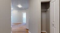 This single-floor residence is thoughtfully designed with a clean, contemporary aesthetic defined by neutral tones, white trim, and a consistent use of light wood-style flooring throughout the main living areas. The open-concept layout connects the living area directly to the kitchen, creating a spacious, functional core at the heart of the unit. Large windows fitted with horizontal blinds allow generous natural light to fill the space while providing views of the surrounding neighborhood.

The kitchen is well-appointed with white shaker-style cabinetry, light quartz countertops, and a full suite of stainless steel appliances, including a refrigerator, electric range, over-the-range microwave, and dishwasher. A central island provides additional counter and prep space. The layout flows efficiently, making it practical for everyday use.

The bedrooms feature soft carpeting, neutral walls, and individual closets equipped with wire shelving systems. One bedroom includes a spacious walk-in closet, adding meaningful storage capacity. The bathroom is finished with a white vanity, light quartz countertop, wood-style flooring, and a full soaking tub with shower. Panel-style interior doors and consistent hardware choices tie the design together throughout the space.