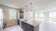 This contemporary single-floor residence showcases a thoughtfully designed open-concept layout that seamlessly connects the kitchen, dining, and living areas. The kitchen serves as a central feature, anchored by a large island with light granite countertops, an undermount sink, and sleek dark cabinetry. Stainless steel appliances, including a range, built-in microwave, dishwasher, and refrigerator, complete the well-appointed space. Stylish pendant lighting hangs above the island, adding warmth and visual interest.

The living area is bathed in natural light, courtesy of expansive floor-to-ceiling windows and glass doors that open to a private balcony offering outdoor views. Light wood-style flooring flows throughout the main living spaces, creating a clean and cohesive aesthetic.

The bedrooms are carpeted for comfort, each featuring a ceiling fan and windows that bring in natural light. The bathroom is finished with matching granite countertops on a double-sink vanity, dark cabinetry, a large mirror, and a walk-in shower.

A dedicated hallway houses a stacked washer and dryer unit, providing in-unit laundry convenience. Throughout the residence, neutral tones, modern finishes, and recessed lighting contribute to a bright, polished, and functional living environment.