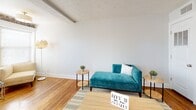 This single-floor unit offers a well-organized layout that combines character-rich design elements with practical functionality. The living room serves as a welcoming focal point, showcasing a striking exposed brick accent wall, warm hardwood flooring, and a textured ceiling. A striped area rug anchors the seating area, while a pass-through opening connects the space to the kitchen, enhancing the open feel.

The kitchen is efficiently designed with rich, dark-stained cabinetry extending to the ceiling for ample storage, stainless steel appliances including a refrigerator, dishwasher, and microwave, plus a convenient in-unit washer. Tile flooring and generous counter space make this a highly functional cooking area.

Two bedrooms feature plush carpeting, soft neutral walls, and flush-mount ceiling fixtures, each providing a quiet and comfortable retreat. Closet access is available in both rooms, supporting practical storage needs.

The bathroom is clean and contemporary, featuring large-format white floor tiles, a dark-finished vanity with an integrated sink, and a full tub-shower combination with tiled surround. Overall, the unit blends classic architectural details with modern finishes throughout.