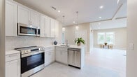 Located at 69 E Central St in Natick, MA, this well-appointed 2-bedroom, 2-bathroom single-floor residence offers a thoughtfully designed open layout. The combined kitchen and living area serves as the heart of the home, showcasing crisp white shaker cabinetry, a subway tile backsplash, quartz countertops, and a peninsula with an undermount sink. Stainless steel appliances, including a refrigerator, range, microwave, and dishwasher, complete the kitchen, which is illuminated by globe pendant lights and recessed lighting. Light-toned tile flooring runs through the kitchen, transitioning to wide-plank hardwood in the expansive living area, where large windows frame views of the surrounding neighborhood and fill the space with natural light. The generously sized primary bedroom features plush carpeting, recessed lighting, and a vaulted ceiling detail, while the second bedroom is equally bright with carpeted floors and outdoor views. Three closets provide ample storage throughout. Both bathrooms are finished in a clean, modern palette, with one featuring a soaking tub, subway tile surround, and light marble-style tile flooring. A dedicated laundry area and a connecting hallway complete the functional floor plan of this move-in-ready Natick residence.