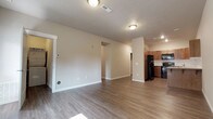 Located at 514 East Hastings Road in Spokane, Washington, this single-floor unit offers a thoughtfully designed layout with a clean, modern aesthetic throughout. The open-concept living area is finished with durable wood-look flooring and neutral-toned walls, creating a bright and versatile space that flows seamlessly toward the kitchen and dining areas. Natural light filters in through the windows, enhancing the unit's welcoming atmosphere.

The kitchen is well-appointed with warm wood cabinetry, white tile backsplash, light countertops, and a full suite of black appliances including a refrigerator, electric range, over-the-range microwave, and dishwasher. A stainless steel sink completes the functional workspace.

Two bathrooms serve the unit — one featuring a walk-in shower with built-in shelving and a wood-toned vanity, and a second with a full soaking tub and shower combo alongside a matching vanity with ample counter space. Both bathrooms continue the wood-look flooring found throughout the main living areas.

The bedrooms are carpeted for comfort and include closet storage. A dedicated utility area houses a stacked Whirlpool washer and dryer alongside a water heater, providing convenient in-unit laundry. The overall design balances practicality with modern finishes throughout.