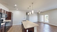 Located at 3 Vantage Way in Greenville, South Carolina, this single-floor, 3-bedroom, 2-bathroom home offers a practical and comfortable layout designed for everyday living. The open-concept kitchen and living area serves as the heart of the home, where rich dark-brown cabinetry, granite-style countertops, a mosaic tile backsplash, and black appliances create a striking kitchen aesthetic. A central island with a built-in sink and elegant pendant lighting adds both functionality and style, while wood-look flooring extends through the main living areas. The living room is bright and inviting, featuring a ceiling fan, large windows with blinds, and glass French doors that open to an outdoor area, flooding the space with natural light and neighborhood views. Each of the three bedrooms is carpeted and equipped with a ceiling fan, offering a comfortable retreat. The bedrooms feature neutral walls and well-sized windows that bring in natural light; one bedroom includes a closet with double doors. The two bathrooms are finished consistently with dark wood vanities, granite-style countertops, wood-look flooring, and shower-tub combinations, providing a clean and cohesive design. Overall, the home presents a bright, neutral palette with modern fixtures throughout.