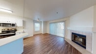Located at 20800 Lake Chabot Rd in Castro Valley, California, this single-floor residence offers a well-designed layout with a clean, modern aesthetic throughout. The living area is anchored by rich wood-look flooring and features a tile-surround fireplace, adding a cozy focal point to the space. Large sliding glass doors dressed with vertical blinds flood the room with natural light and provide access to the outdoors, while an additional window enhances the bright, airy feel. Track lighting overhead adds a contemporary touch.

The kitchen is thoughtfully appointed with white shaker-style cabinetry, light countertops, and a full suite of stainless steel appliances including a gas range, microwave, dishwasher, and refrigerator. A peninsula with a breakfast bar connects the kitchen to the living and dining areas, creating an open, functional flow. Wood-look flooring continues throughout the main living spaces.

The bedroom offers a quieter retreat with plush carpeting, dual windows allowing ample natural light, and a baseboard heating unit for year-round comfort. The bathroom is clean and efficiently designed, featuring wood-look flooring, a full tub and shower with white tile surround, a white vanity, and high transom windows that allow light while maintaining privacy.