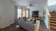 This two-story residence at 170 Highlands Blvd in Savannah, Georgia offers a thoughtfully designed layout with stylish finishes throughout. The kitchen is a standout feature, equipped with stainless steel appliances including a French door refrigerator, range, and over-the-range microwave, complemented by rich dark cabinetry, quartz countertops, a glass tile backsplash, and a central island ideal for meal prep and casual dining. Natural light flows in through a nearby window, and hardwood-style flooring ties the space together seamlessly. The open living area is bright and inviting, featuring dark hardwood-style floors, crown molding, a ceiling fan, and large windows that frame outdoor views. A wall-mounted media console adds a warm, modern focal point to the room. The bedrooms are carpeted and feature tray ceilings with ceiling fans. The primary bedroom includes access to a walk-in closet. Secondary bedrooms offer versatile space suitable for sleeping or a home office setup. The bathrooms are finished with dark vanity cabinetry, quartz countertops, and hardwood-style flooring, with tub-shower combinations. A dedicated laundry room with full-size washer and dryer, built-in shelving, and a window completes this well-appointed home.