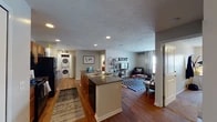 This single-floor residence at 1839 Ashton Ln in Kent, Ohio offers a well-organized, open-concept layout that connects the kitchen, dining area, and living room into one cohesive living space. The kitchen is equipped with dark granite countertops, a central island with a sink, warm wood cabinetry, black appliances including a refrigerator and microwave, and recessed lighting overhead. A dedicated dining area sits adjacent to the kitchen, providing a practical space for meals. The living room features hardwood-style flooring, a large window that allows natural light to fill the space, and a textured ceiling throughout. A stacked washer and dryer unit is conveniently integrated within the main living area. Two bedrooms offer carpet flooring, natural light through blinded windows, built-in shelving, and a built-in desk workspace in one room. Two full bathrooms feature granite-topped vanities with wood cabinetry, tile flooring, large mirrors with overhead lighting, and ample storage. The overall ambiance is functional and comfortable, well-suited for everyday living in the Kent, Ohio area.