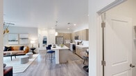 This well-appointed single-story residence offers two bedrooms and two bathrooms within a thoughtfully designed open-concept floor plan. The kitchen serves as a central hub, featuring light wood-toned cabinetry extending to the ceiling, quartz countertops with a white tile backsplash, stainless steel appliances, and a large center island with bar seating and a single-basin sink, illuminated by modern pendant lighting. Wood-look flooring flows through the kitchen and living areas, lending a cohesive, contemporary feel.

The living room is bright and comfortable, with a ceiling fan, neutral walls, and sliding glass doors that open to an outdoor patio, inviting natural light into the space. Both bedrooms feature plush carpeting and ceiling fans. The primary bedroom includes a dedicated closet with built-in shelving and hanging rods, alongside an en-suite bathroom. Each bathroom is finished with a wood-toned floating vanity, quartz countertops, and a tub-shower combination.

A dedicated in-unit laundry room houses a full-size washer and dryer with built-in shelving above, adding practical convenience. Throughout the residence, clean white walls, recessed lighting, and consistent modern finishes create a polished, cohesive aesthetic.