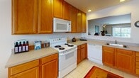 Located at 100 Cindy Dr in Newark, Delaware, this single-floor home offers a well-organized and functional layout connecting living, dining, kitchen, and sleeping areas through a carpeted hallway. The living room is a welcoming centerpiece, featuring warm beige walls, plush carpeting, and a fireplace that serves as a natural focal point. A pass-through window connects the living area to the kitchen, enhancing the open feel between spaces. The kitchen is outfitted with rich honey-toned wood cabinetry extending to the ceiling, providing ample storage. White appliances including a range, built-in microwave, and dishwasher complement light countertops and tile flooring. The home includes multiple bedrooms, each carpeted or finished with hardwood-style flooring, ceiling fans with light fixtures, and closet storage. The bedrooms feature neutral wall tones that create a calm and restful atmosphere. The bathroom includes a full tub and shower combination with clean white fixtures. Throughout the home, a consistent palette of warm neutrals and white trim creates a cohesive and inviting ambiance, making this a comfortable and practical single-floor residence.