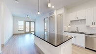 Located at 10221 Whistle Stop Lane in Frisco, TX, this well-appointed 2-bedroom, 2-bathroom residence offers a thoughtfully designed single-floor layout. The open-concept living area seamlessly connects the dining room, kitchen, and living room, creating an inviting and functional space bathed in natural light from large windows and glass doors that open to a balcony. The kitchen is a standout feature, showcasing white shaker cabinetry, a classic subway tile backsplash, dark granite countertops, stainless steel appliances, and a generously sized center island with pendant lighting overhead. A built-in mudroom nook near the entry provides convenient shelving and a bench. The primary bedroom features light hardwood-style flooring, a ceiling fan, and direct access to the outdoors, while the second bedroom offers plush carpeting and ample natural light. Both bedrooms include dedicated closets. The bathrooms are finished with dark granite vanities and tile surrounds. Additional highlights include a pantry, laundry room, utility room, and two closets. The clean, neutral palette and modern finishes throughout lend the space a bright, contemporary ambiance ideal for comfortable everyday living.
