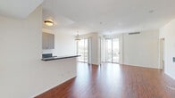 Located in the desirable Brentwood neighborhood of Los Angeles, this well-appointed 2-bedroom, 3-bathroom residence offers a thoughtfully designed layout filled with natural light. Rich hardwood flooring flows throughout the main living areas, creating a warm and cohesive aesthetic against the crisp white walls.

The open-concept living and dining area is expansive and airy, with large sliding glass doors that connect seamlessly to a private balcony. From the balcony, ornate blue ironwork railings frame sweeping views of the Los Angeles skyline and surrounding neighborhood, including palm tree-lined streets below.

The kitchen is well-equipped with gray flat-front cabinetry, dark granite countertops, stainless steel appliances including a refrigerator and dishwasher, and a breakfast bar peninsula that opens to the living area. Tile flooring grounds the kitchen space distinctly.

Both bedrooms are generously sized, featuring hardwood floors and mirrored sliding closet doors. The primary bedroom is notably spacious, with ample room for furnishings. The unit includes three bathrooms: one features a clean walk-in shower with frosted glass, while another offers a tub/shower combo with a granite-topped vanity and a backlit mirror. An abundance of closet space — eight closets in total — provides exceptional storage throughout.