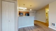 Located at 12950 E Mansfield Ave in Spokane Valley, WA, this single-floor, 2-bedroom, 1-bathroom unit offers a practical and well-organized layout. Hard surface flooring runs throughout the entire unit, providing a cohesive look and easy maintenance across all rooms.

The open-concept kitchen and living area forms the heart of the unit. The kitchen features warm wood cabinetry, black appliances including a refrigerator and microwave, and a peninsula with a light countertop that separates it from the living space. Three pendant lights hang above, adding focused illumination to the area. A sliding glass door in the living room allows natural light to filter in and provides outdoor access.

The primary bedroom includes a dedicated closet with wire shelving for organized storage. The second bedroom features a window with views of the surrounding outdoor area, allowing natural light to brighten the space.

The bathroom includes a wood-toned vanity with a large mirror, light bar, and light countertop. Conveniently adjacent to the bathroom is the in-unit laundry area, equipped with a full-size washer and dryer and overhead wire shelving. A dedicated closet elsewhere in the unit provides additional storage capacity.